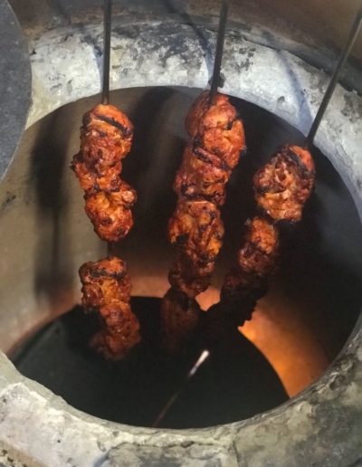 Tandoori chicken being lowered into the Indian oven